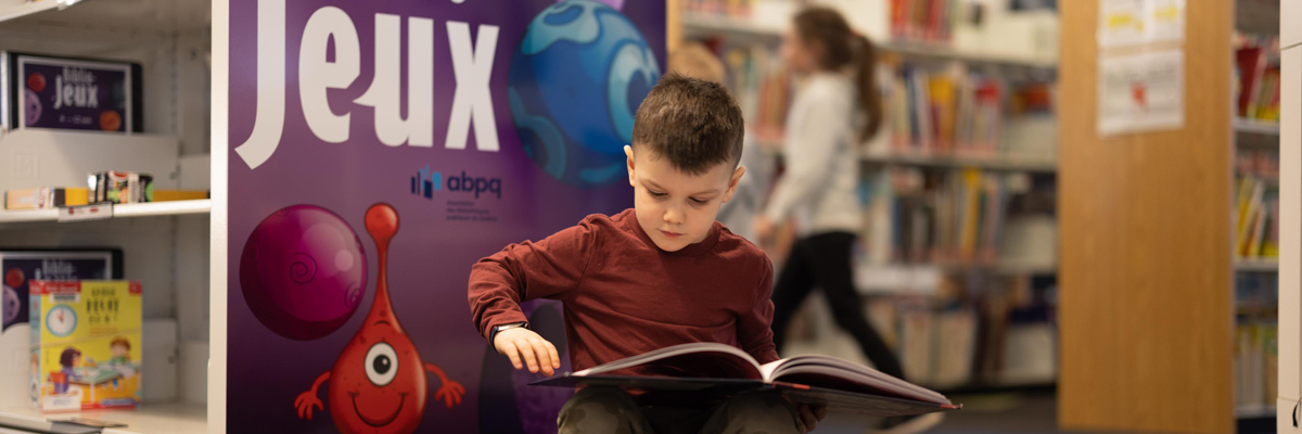 Garçon qui lit à la bibliothèque
