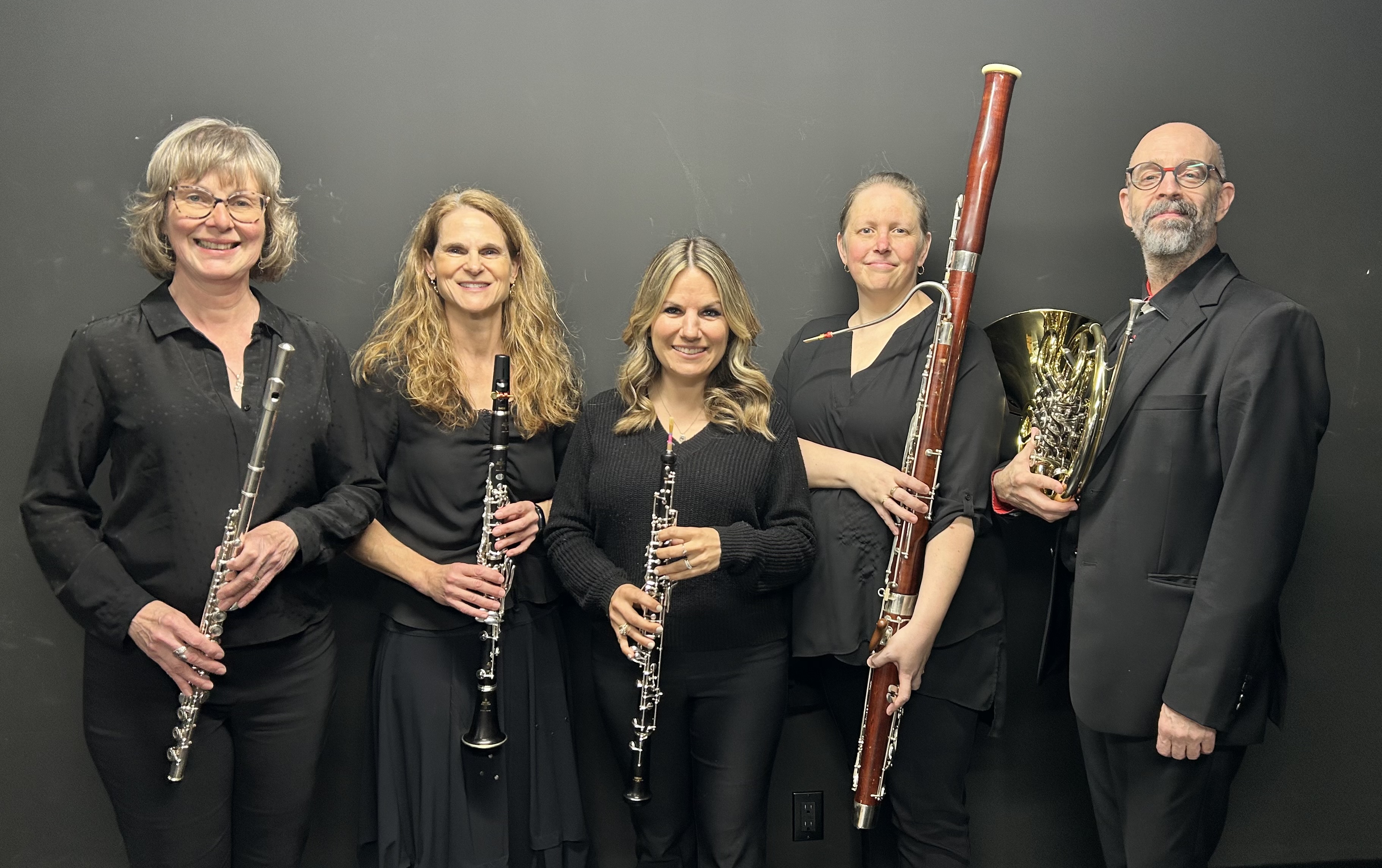 Cinq membres d’un ensemble à vent, chacun tenant un instrument : flûte traversière, clarinette, hautbois, basson et cor.