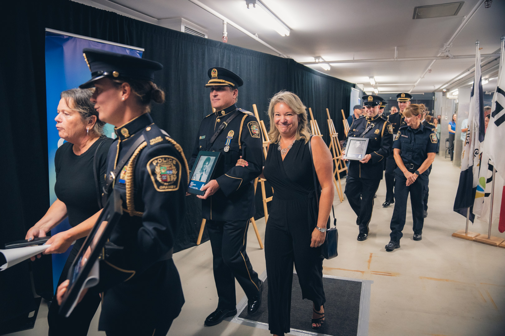 Défilé de personnes, dont des policiers en uniforme, tenant des cadres avec photos lors d’un hommage.