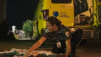 Secouriste agenouillé sur la chaussée, disposant une couverture au sol.